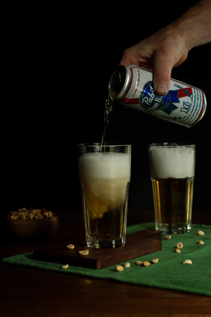 black background and a picture of a hand pouring beer into a glass