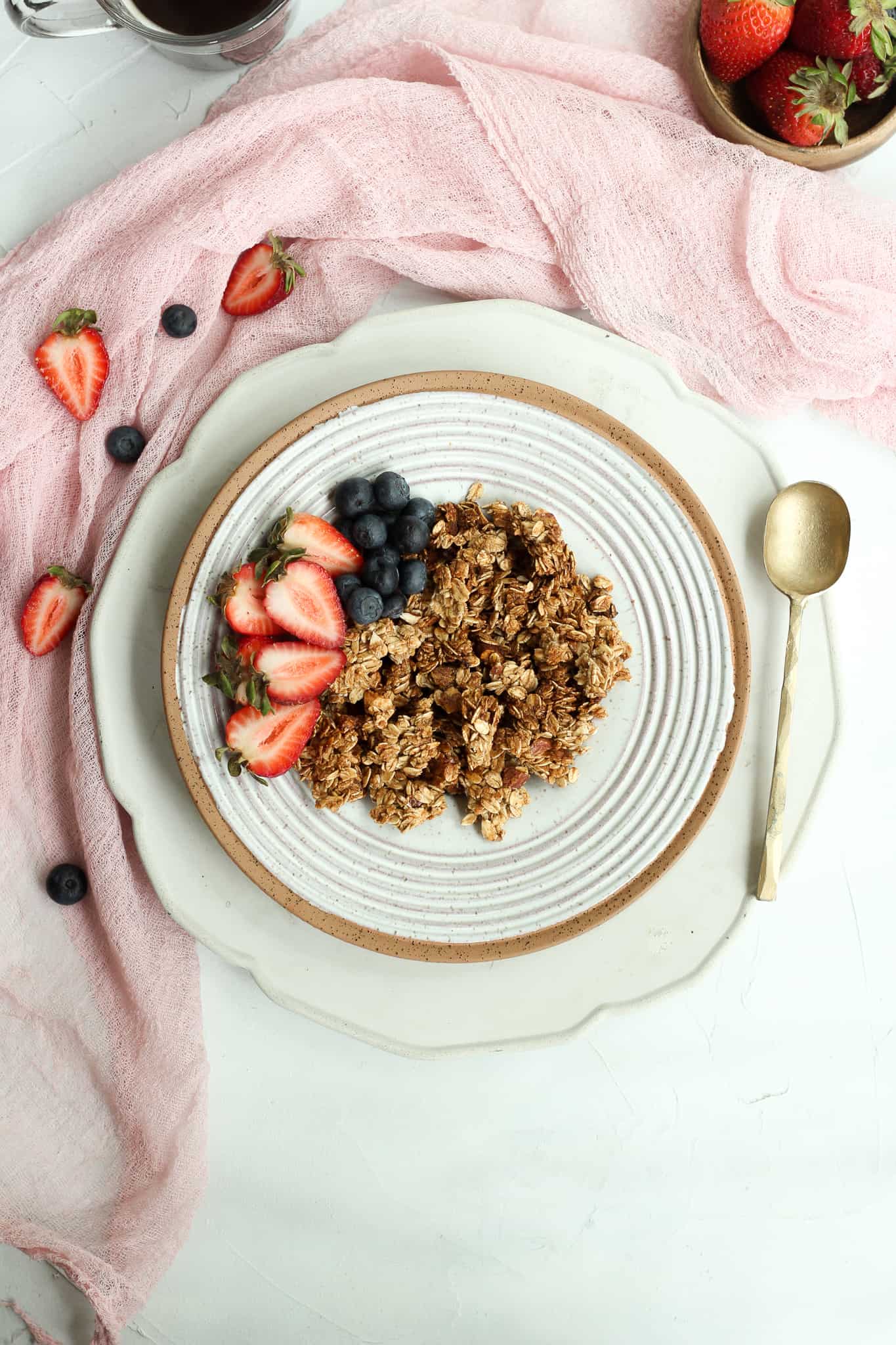 granola in a gray bowl with a gold spoon and a pink napkin