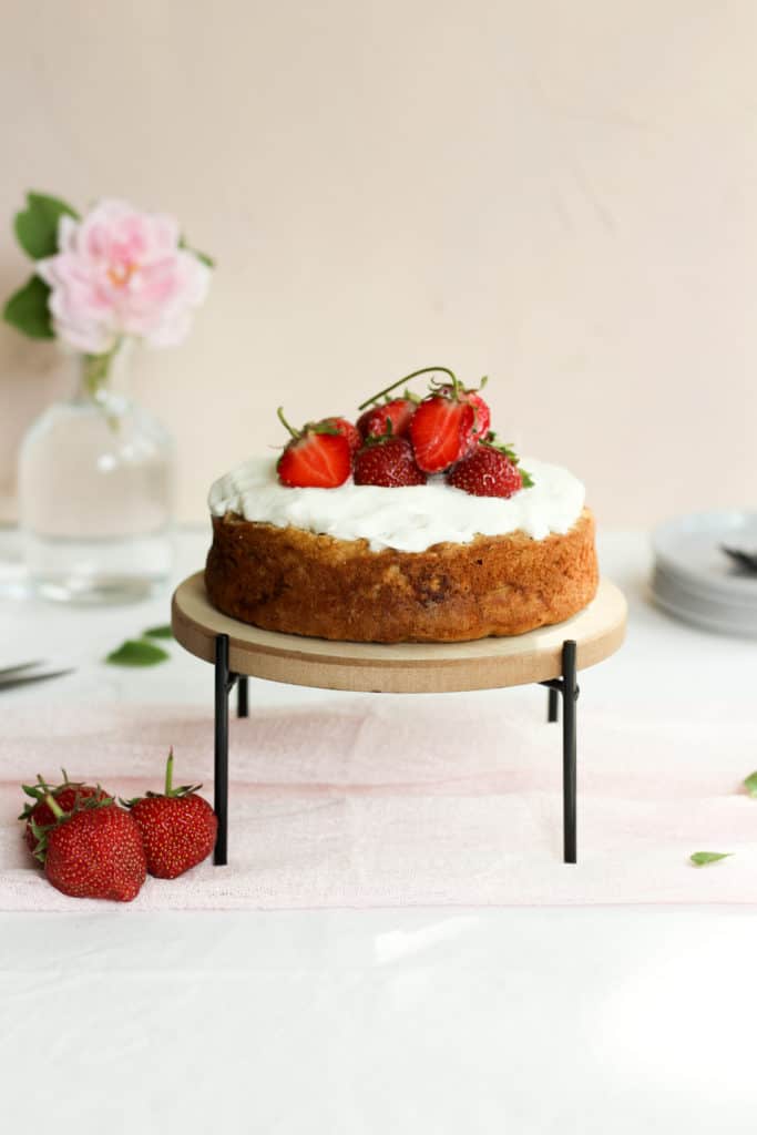 strawberry shortcake on a cake stand topped with whipped cream and strawberries