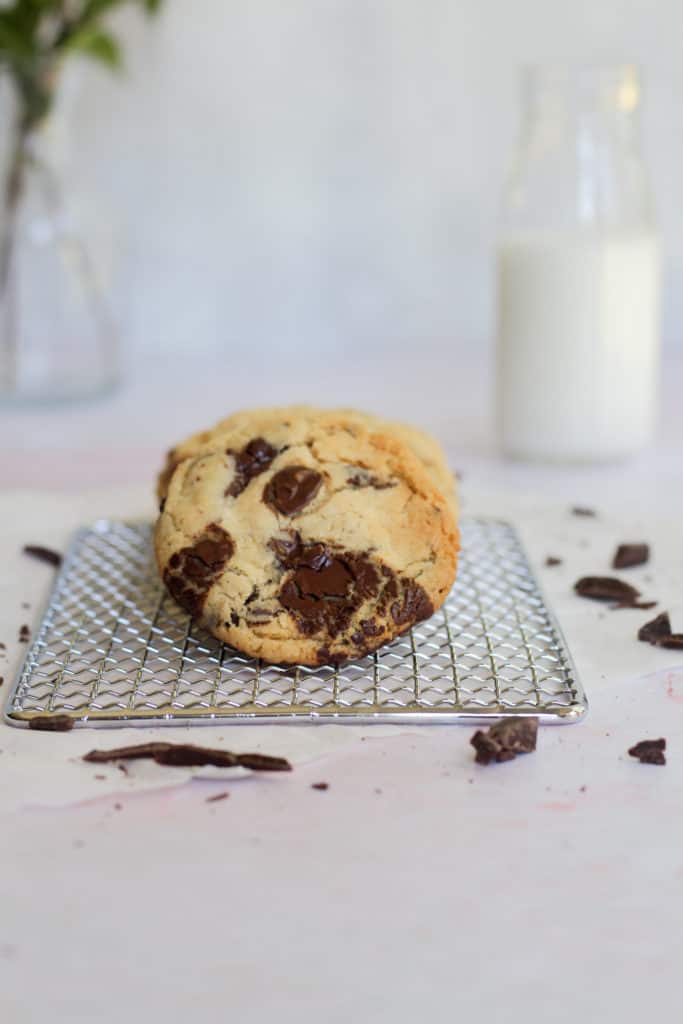 chocolate chip cookie on a cooling rack with a pink backdrop
