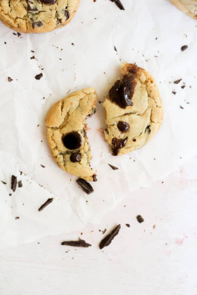 chocolate chip cookie brown in two pieces on parchment paper