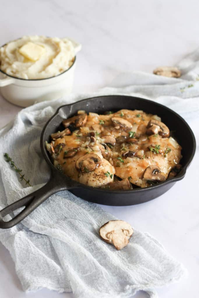 chicken marsala in a cast iron skillet with a blue linen