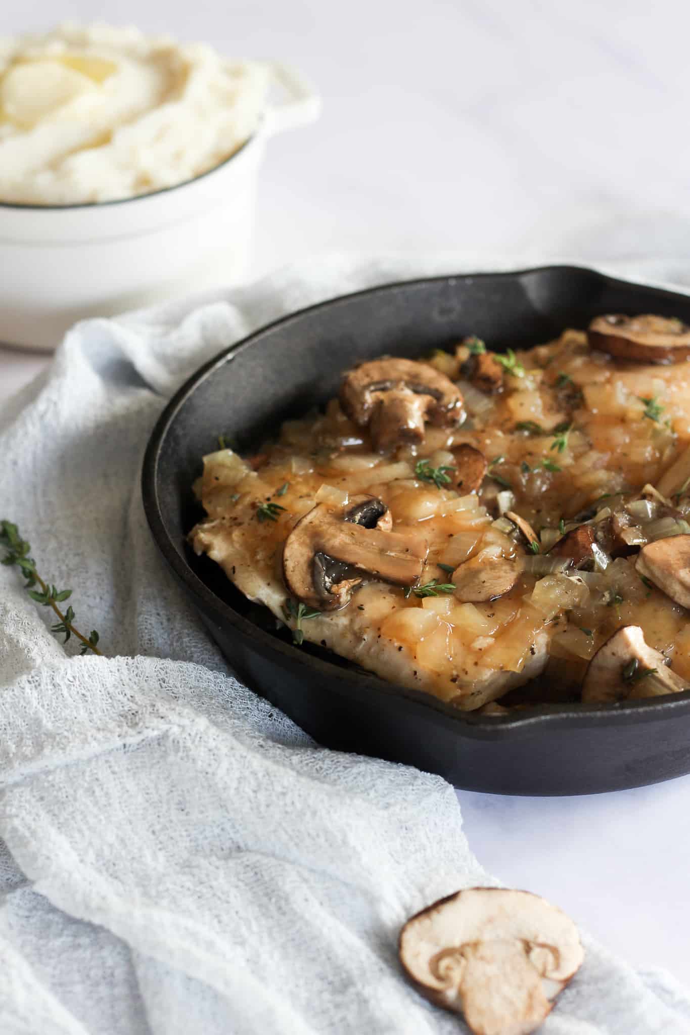 close up of dairy free chicken marsala in a cast iron skillet on a white backdrop