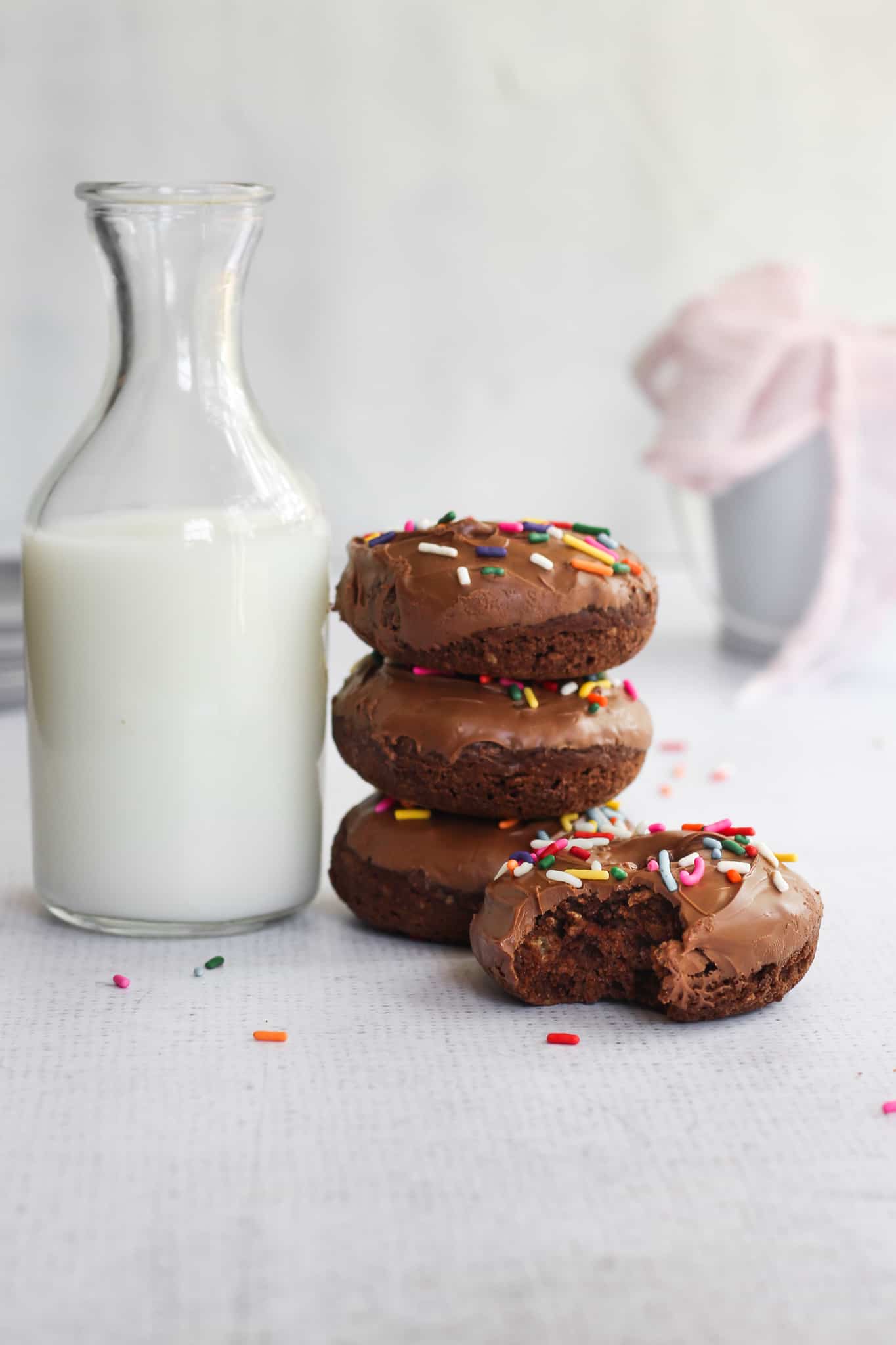 stack of chocolate donuts next to milk jug