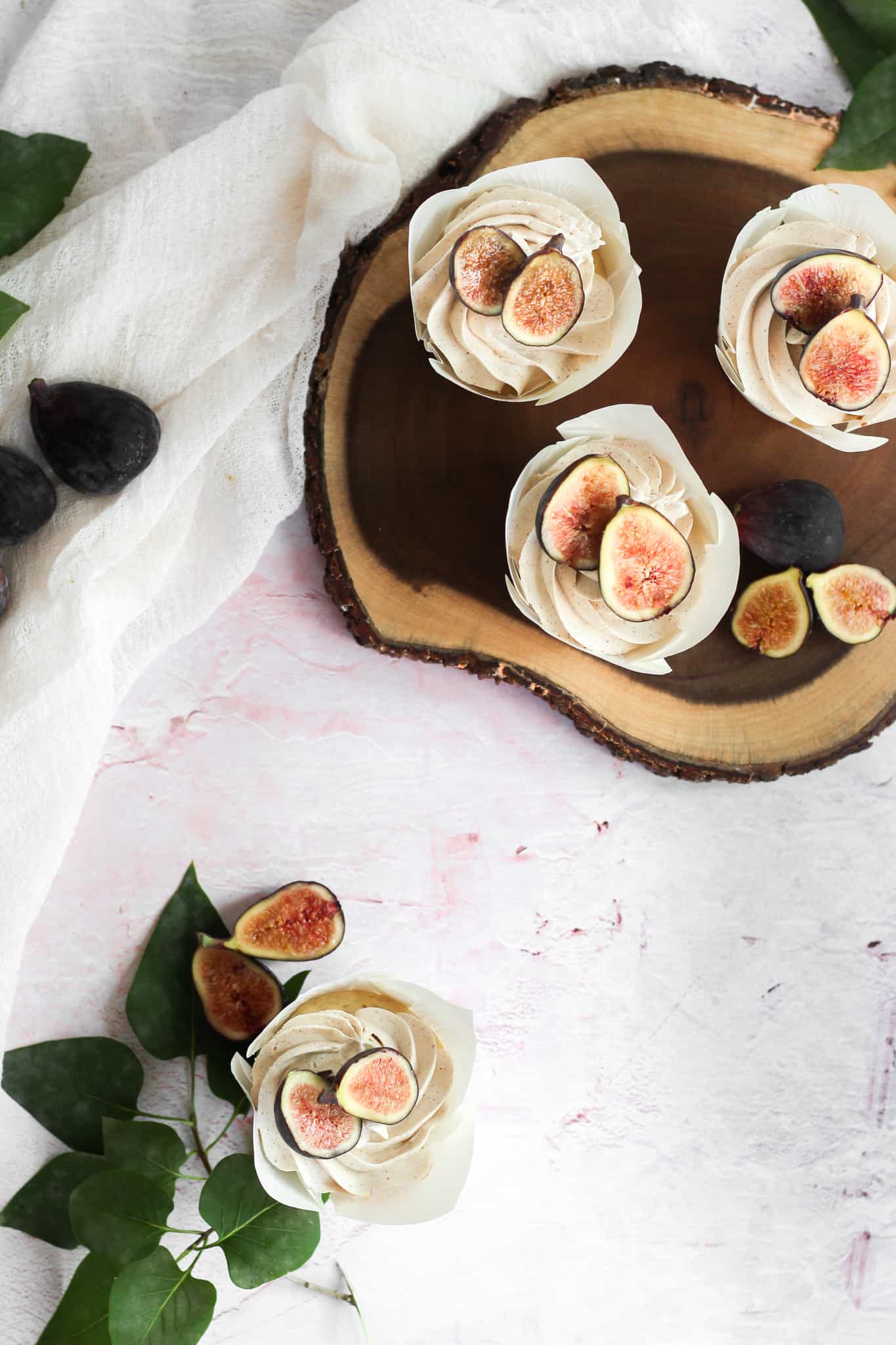vanilla cupcakes topped with figs on a wood board