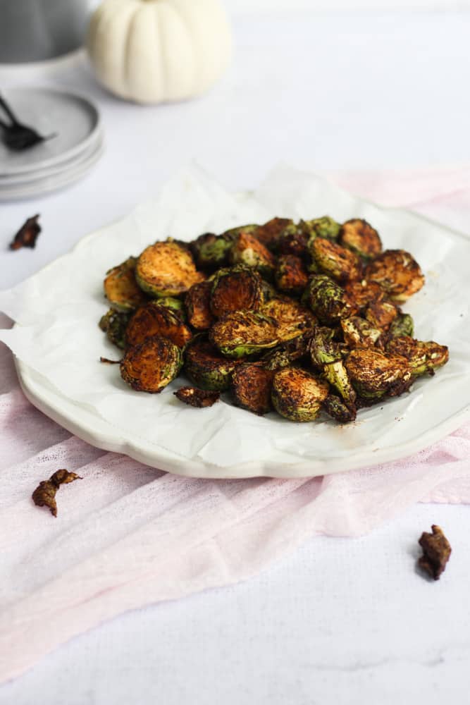 white plate with air fryer brussels sprouts on pink linen