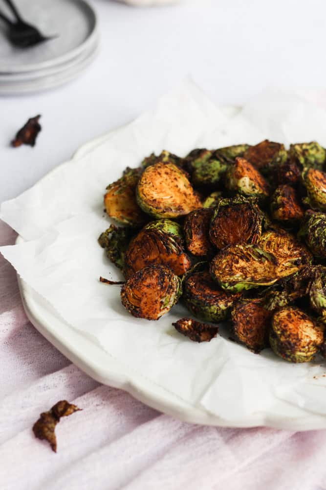 white plate with parchment paper on it full of 15 minute air-fryer brussels sprouts