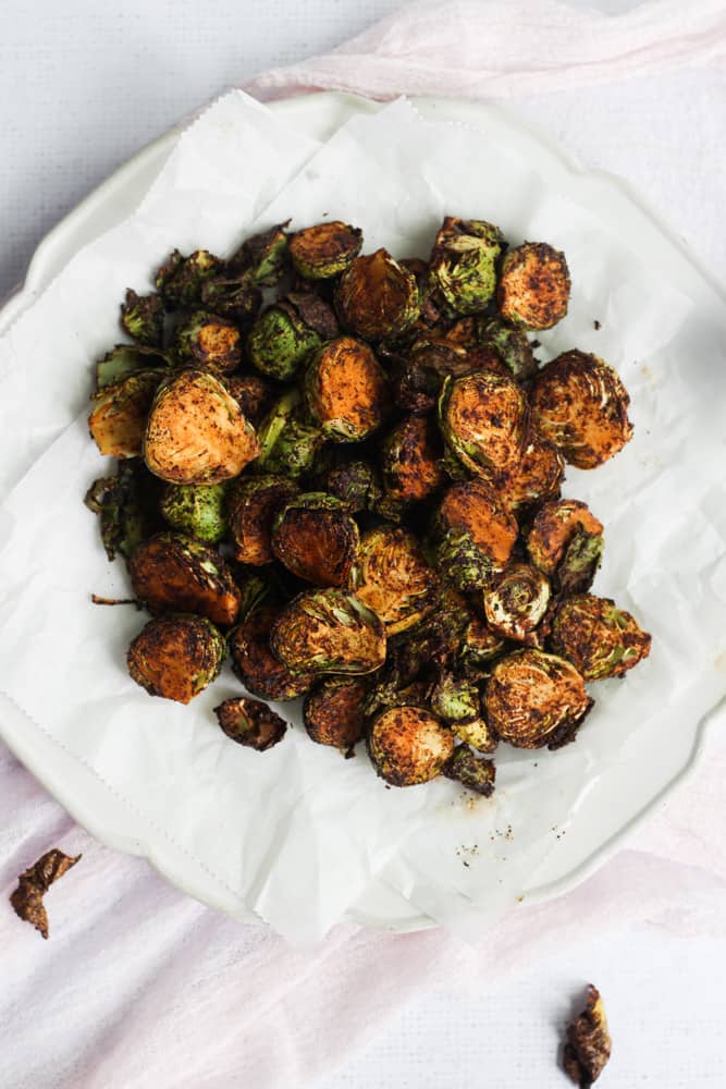 White plate of air-fryer brussels sprouts on a pink napkin