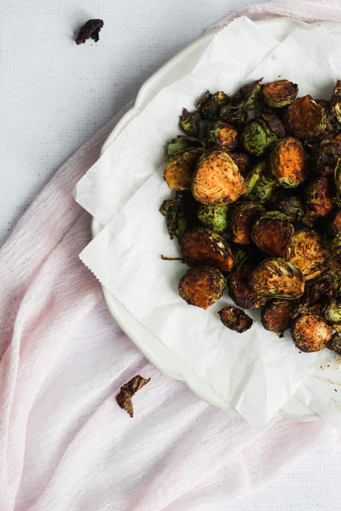 air fryer brussels sprouts on a white plate with a pink napkin underneath