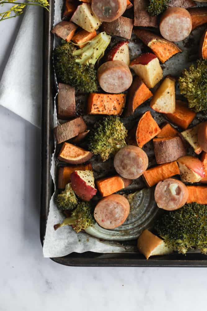 bird's eye view of corner of sheet pan filled with healthy roasted vegetables and lean chicken sausage