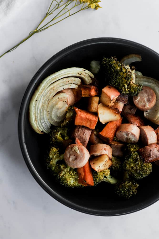black bowl on white backdrop filled with healthy chicken apple sausage and roasted vegetables