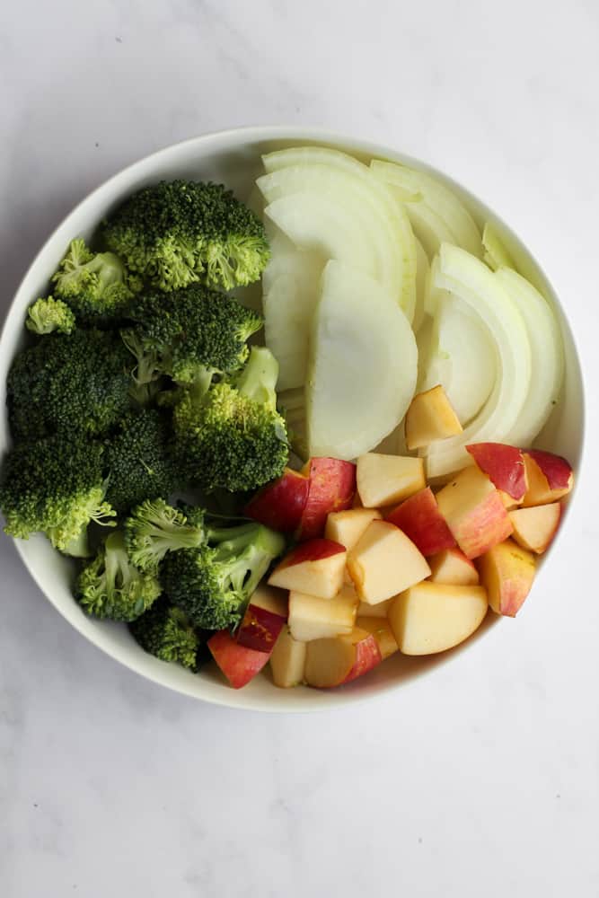 white bowl filled with cut broccoli, sliced onion, and diced apples