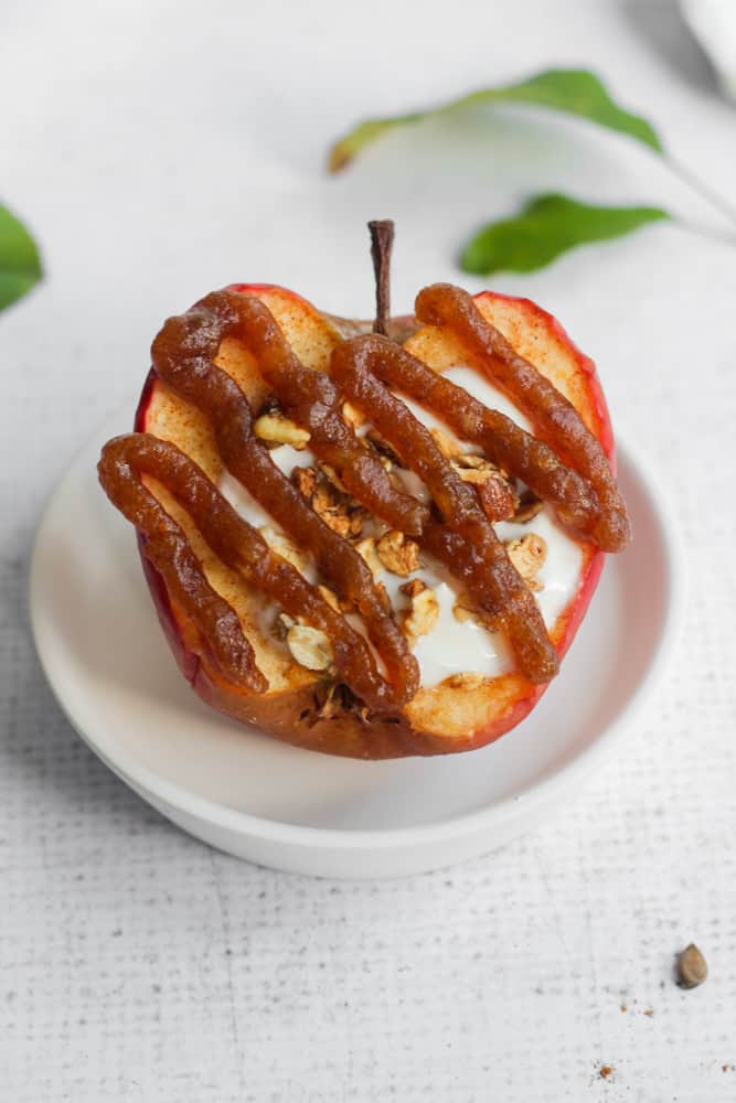 healthy baked caramel apple drizzled with date caramel on a white plate