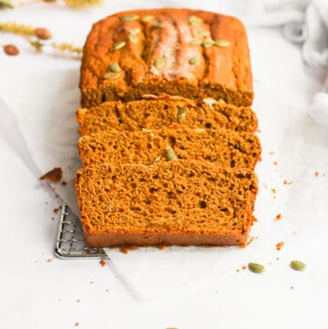 healthy pumpkin bread sliced on a piece of parchment paper.