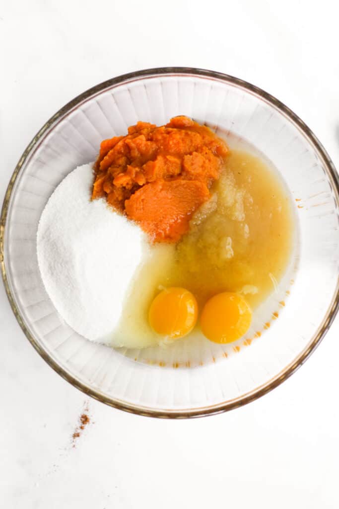 pumpkin, eggs, applesauce, and sugar in a glass bowl.