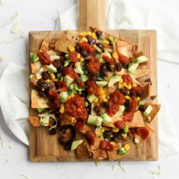 air fryer nachos on a square wooden cutting board.