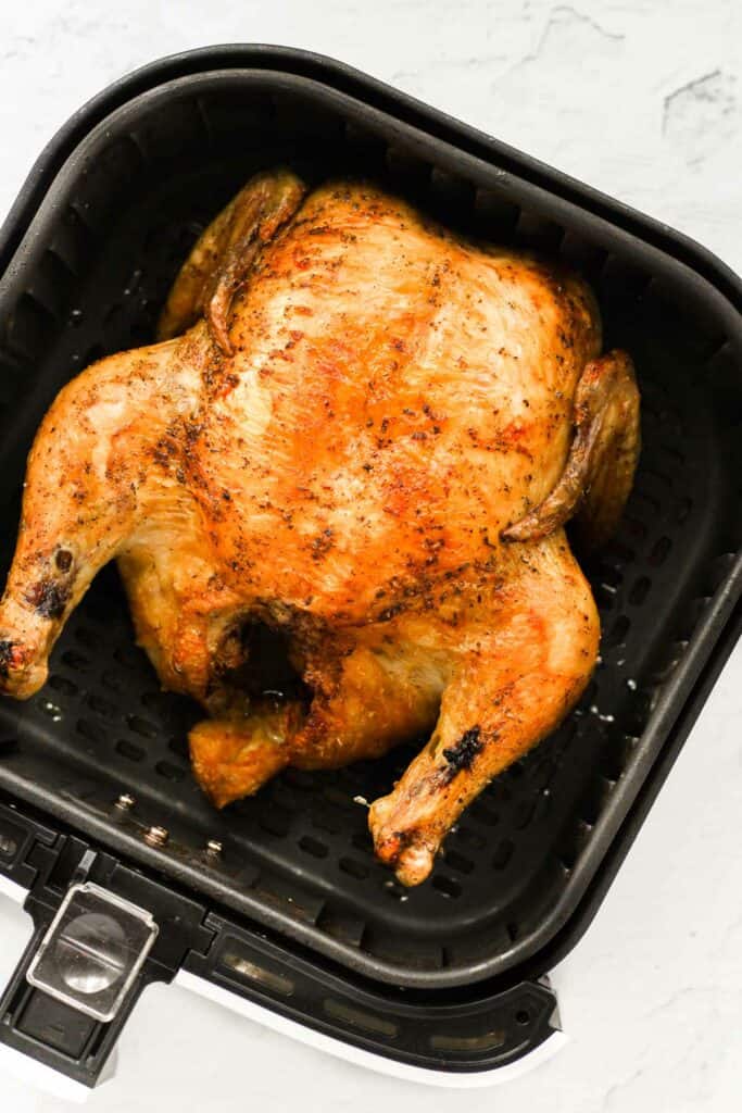 whole chicken cooked in air fryer basket.