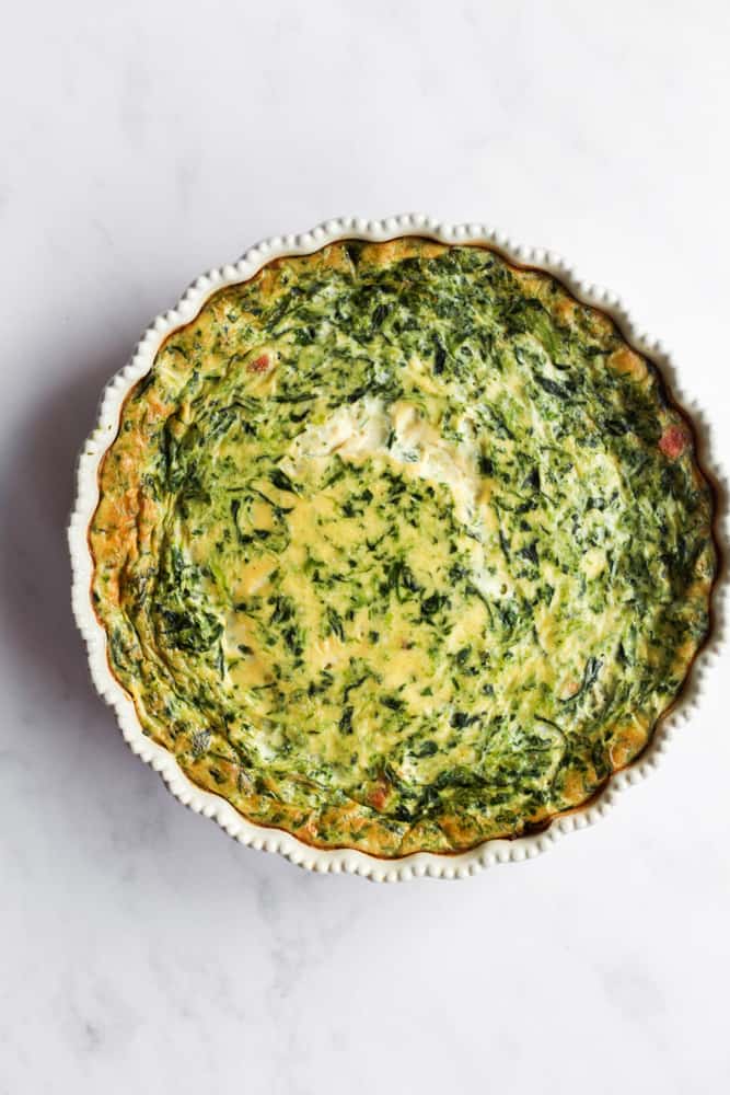 baked healthy, crustless ham and spinach quiche on a white backrop