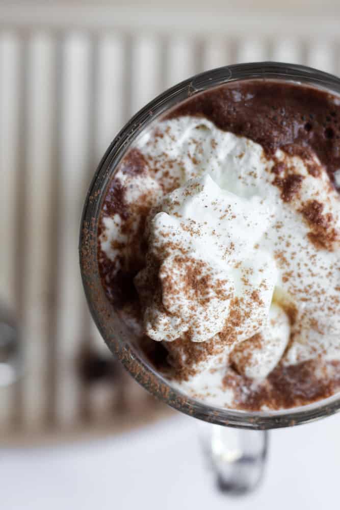 glass mug of paleo hot chocolate topped with whipped cream and cocoa powder