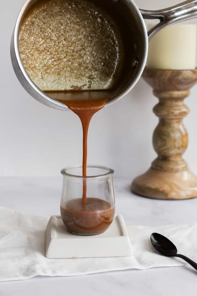 peanut butter caramel being poured from a pot into a glass jar