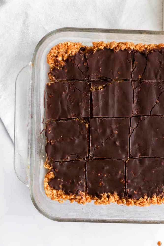3 ingredient peanut butter caramel bars covered in chocolate in a glass baking dish