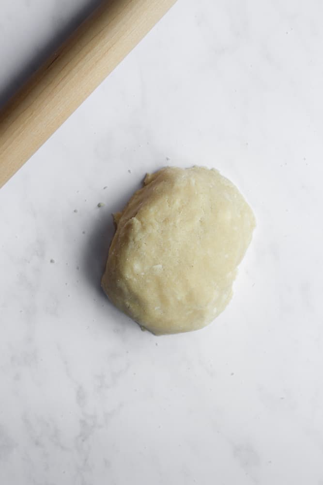 sugar cookie dough on a white backdrop with a wood rolling pin