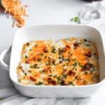 twice baked cauliflower casserole in a white baking dish with a blue linen