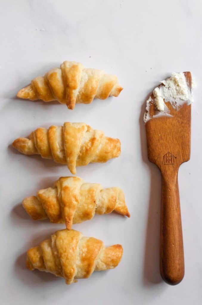 homemade air fryer crescent rolls on a whtie backdrop with a butter knife