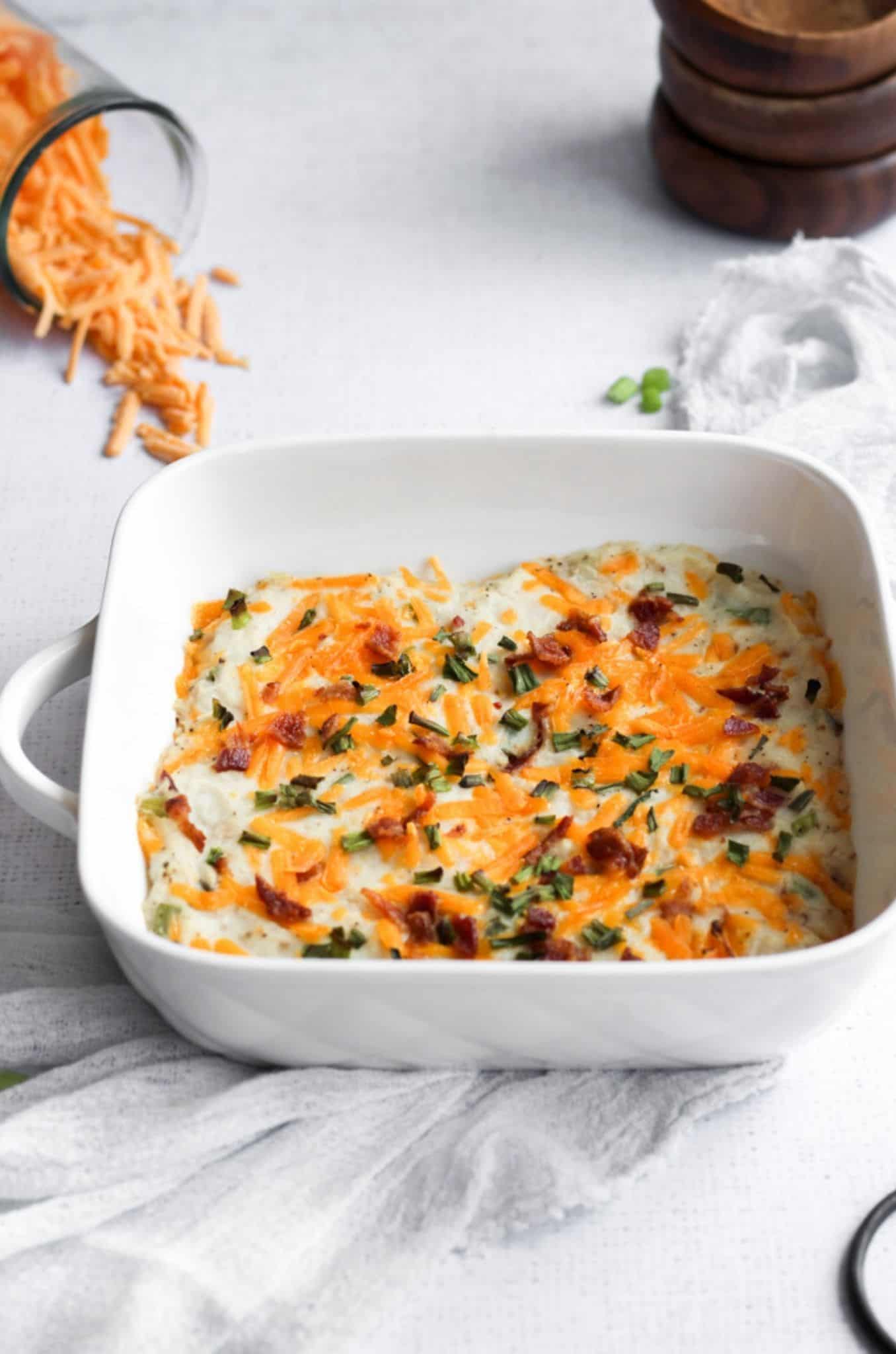 twice baked cauliflower casserole in a white square baking dish on a blue linen