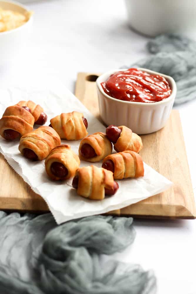 air fryer pigs in a blanket on parchment paper with a bowl of ketchup