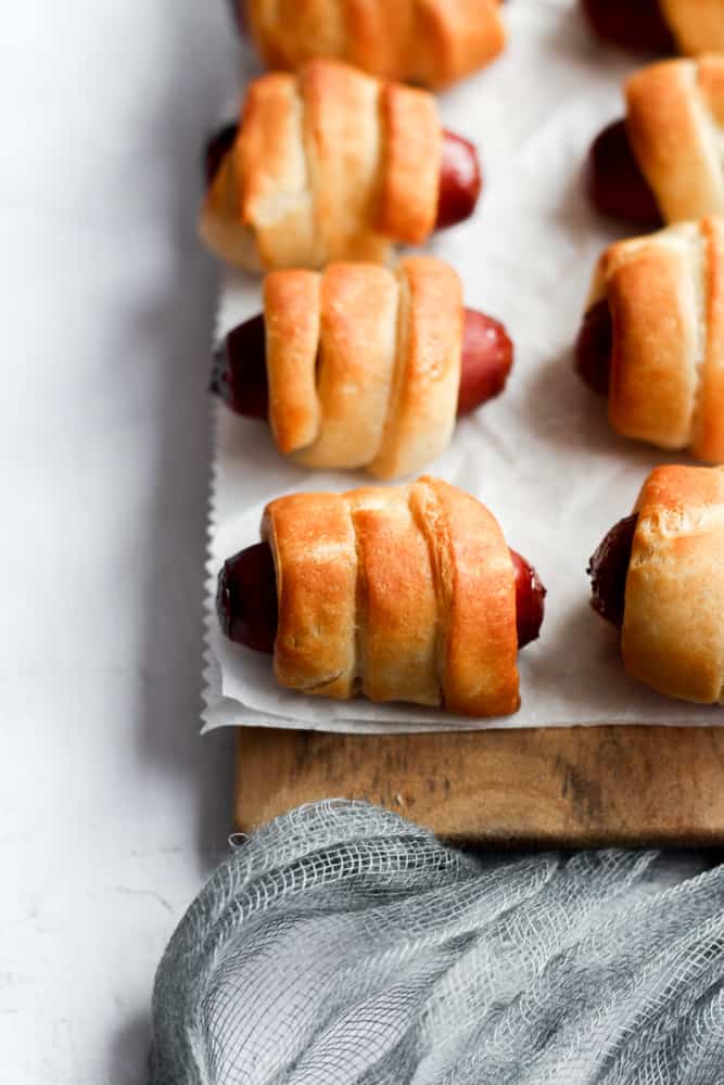 easy pigs in a blanket cooked in the air fryer lined up on a piece of parchment paper