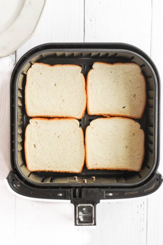 4 slices of white bread in air fryer basket.