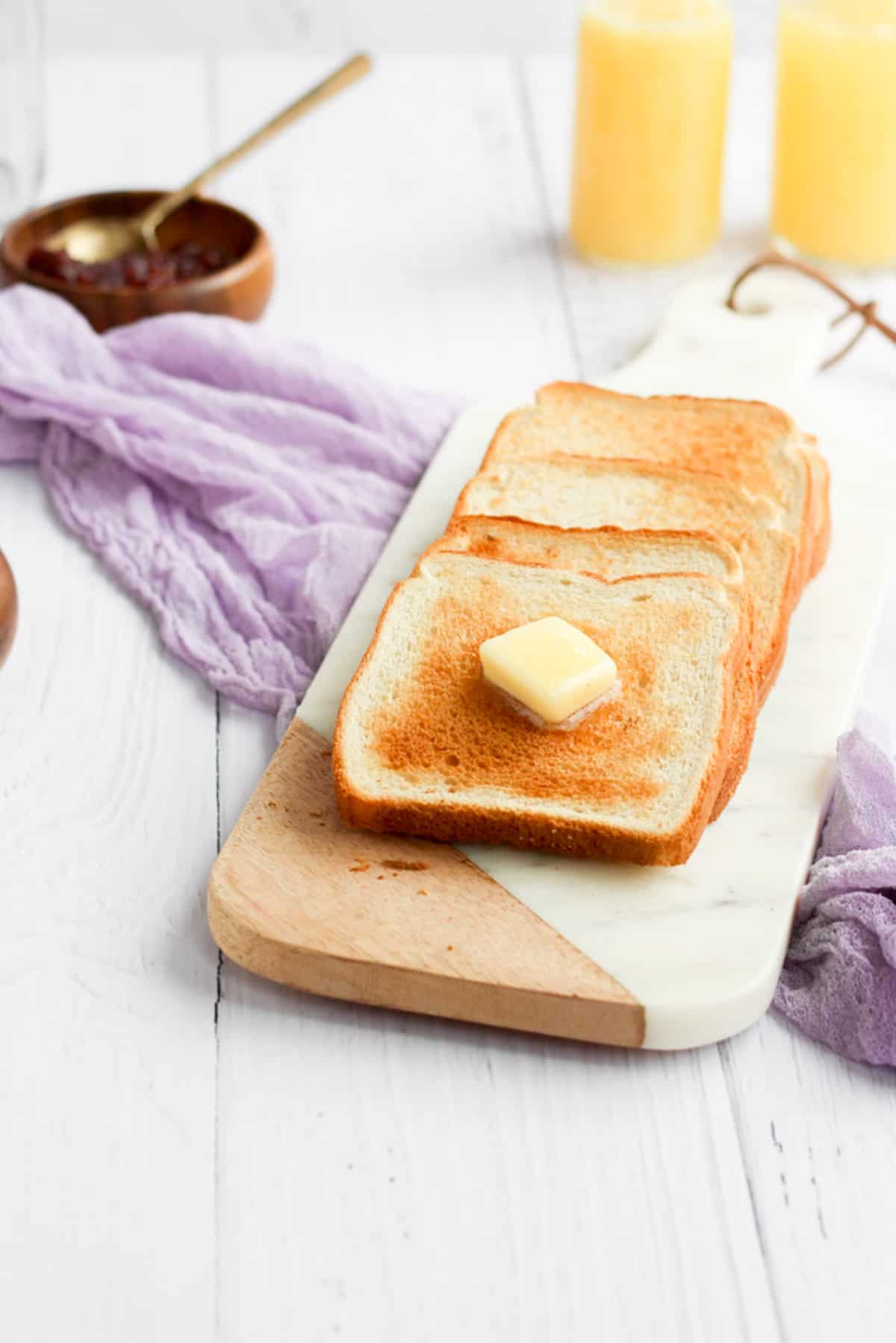 air fryer toast on a cutting board with butter.