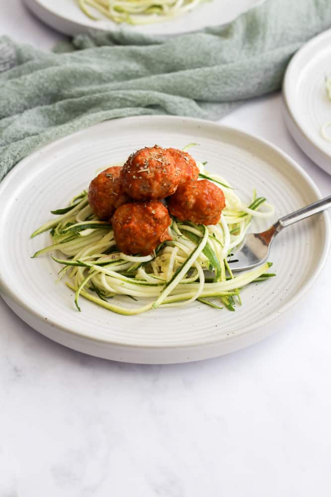 easy turkey meatballs served over zoodles on a white plate with a green napkin under it