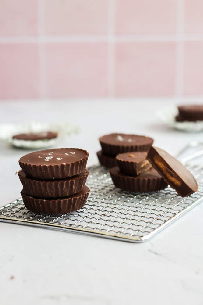 vegan almond butter cups stacked on a cooling rack on a white backdrop