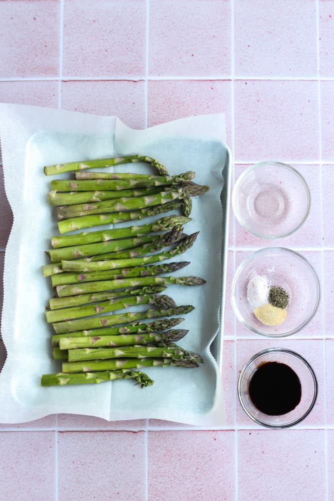 air fryer asparagus ingredients displayed on a pink backdrop