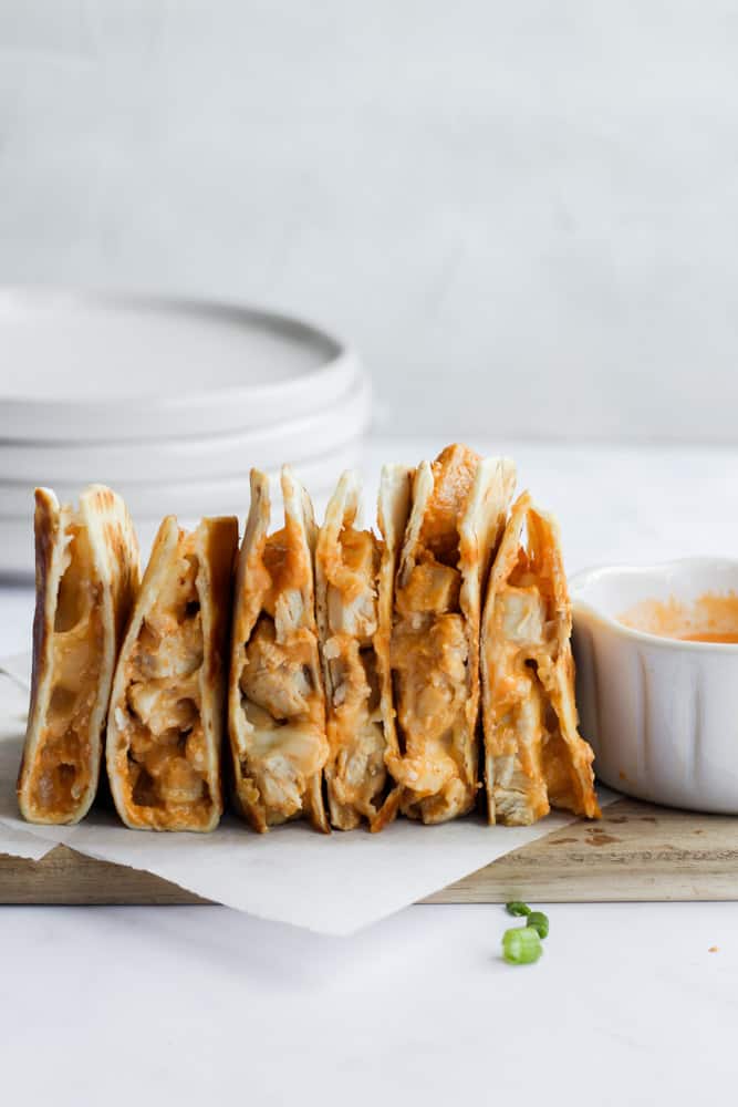 healthy buffalo chicken quesadillas standing on end on parchment paper
