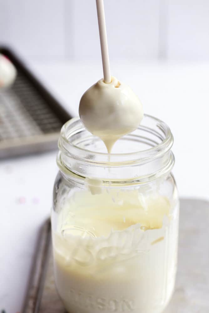 healthy cake pop being dipped in melted white chocolate