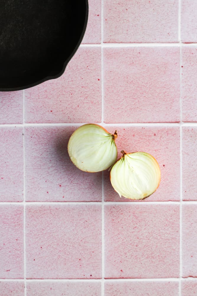 onion cut in half a placed on a pink tile backdrop