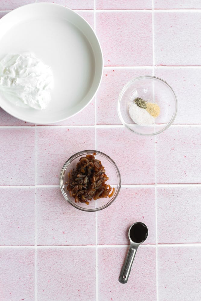 Greek yogurt French onion dip ingredients on a pink tile backdrop