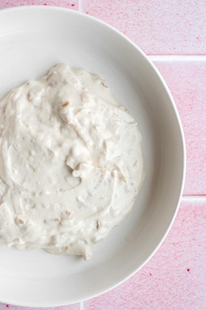 healthy dip in a white bowl on a pink backdrop