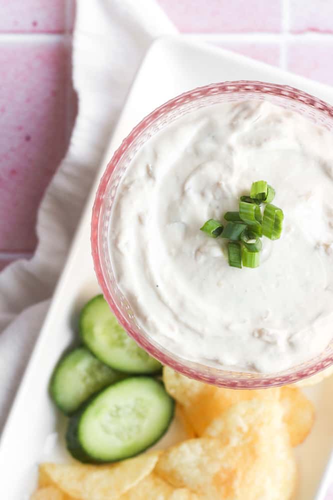 bird's eye view of healthy French onion dip topped with scallions in a pink glass bowl