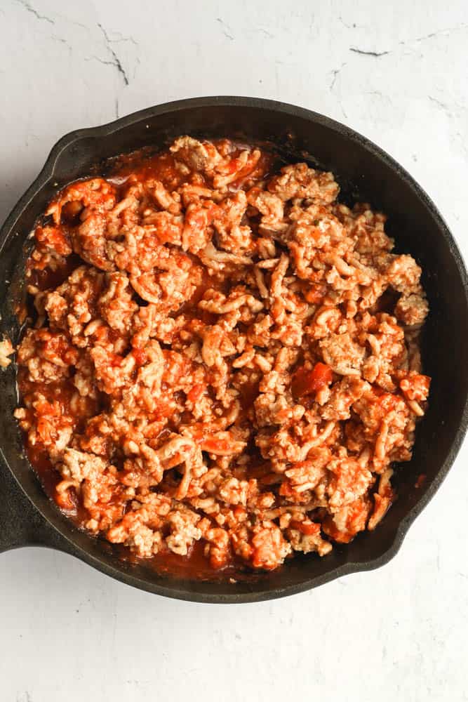 cooked ground chicken mixed with tomato sauce in a cast iron skillet