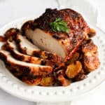 air fryer pork loin sliced and served over baby potatoes on a white platter on top of a white countertop