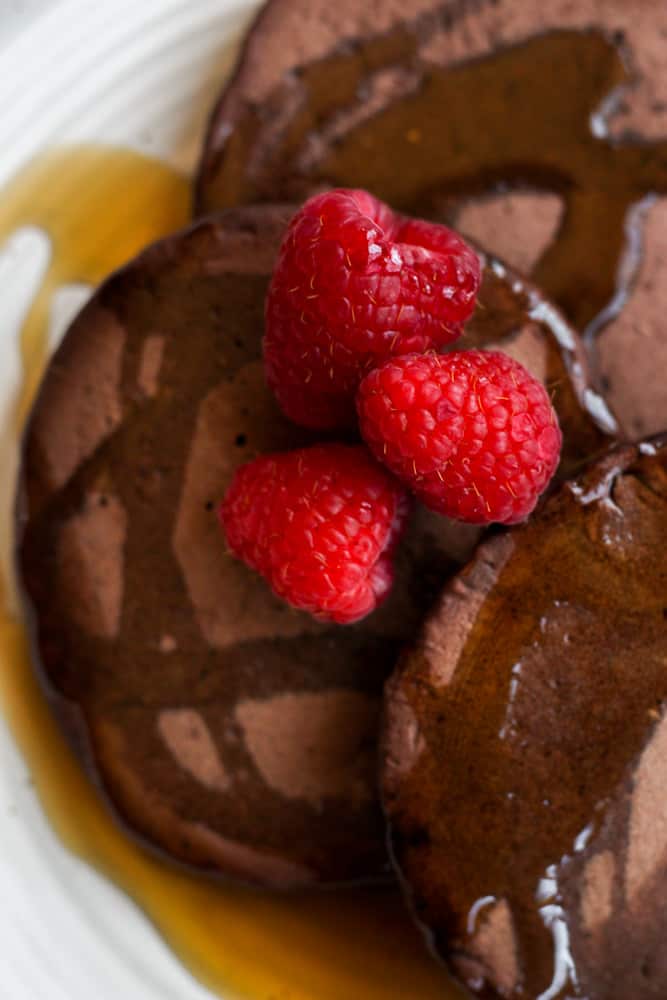raspberries on top of syrup covered chocolate pancakes