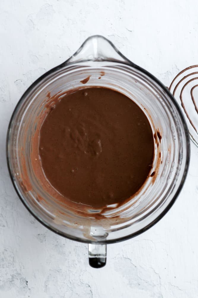 healthy chocolate pancake batter in a glass bowl on a white backdrop
