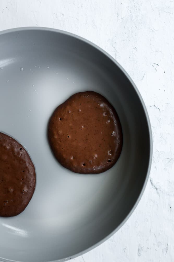 chocolate pancakes cooking in a gray pan