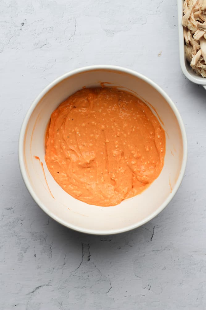 healthy buffalo chicken dip filling in a white bowl on a grayish backdrop