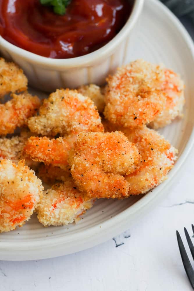 gluten free fried shrimp cooked in the air fryer served on a white plate with a white bowl of ketchup