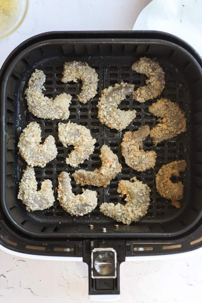 raw breaded shrimp in the basket of an air fryer